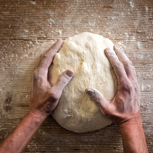 Kneading dough to make bread in a pizza oven