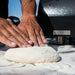 ALFA Classico 2 Pizza Gas oven in background while man is kneading pizza dough by hand on a prep table outside