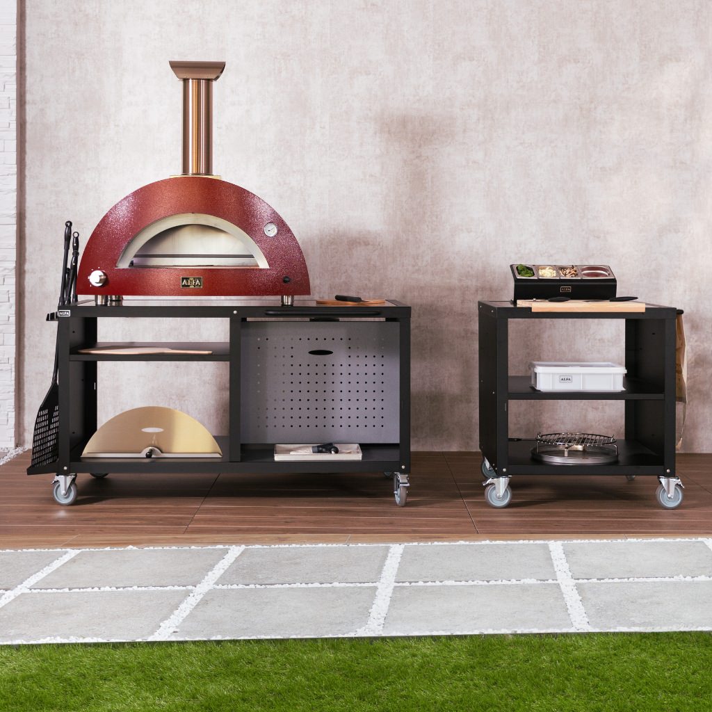Alfa Cooking Station in modern outdoor kitchen with red gas pizza oven on top and various pizza oven accessories on the cooking station.