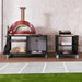 Alfa Cooking Station in modern outdoor kitchen with red gas pizza oven on top and various pizza oven accessories on the cooking station.