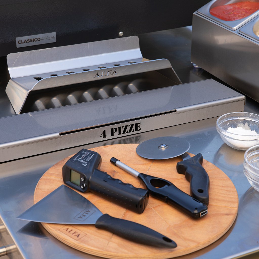 Alfa Kit Hybrid on pizza prep table with wood cutting board, pizza cutter, and infrared thermometer.