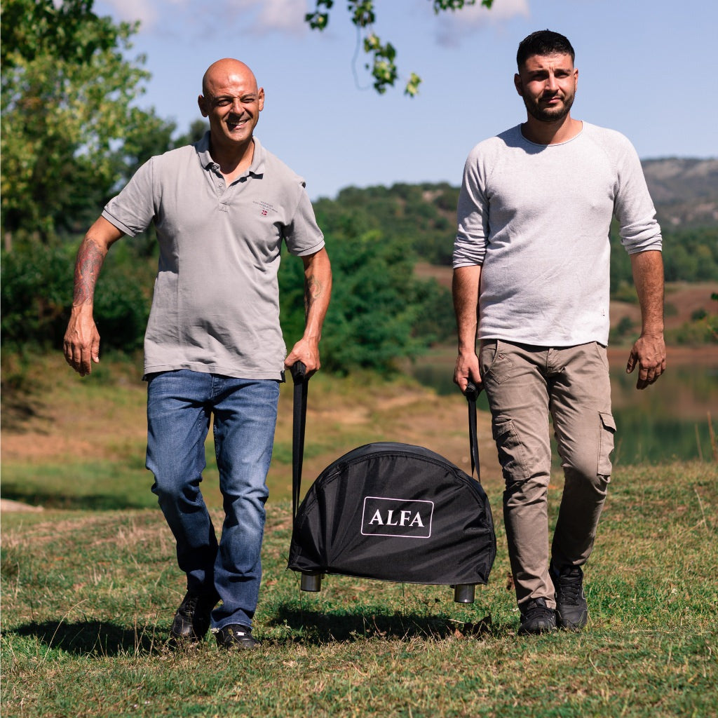 Alfa Moderno Portable Cover with two men walking in a grassy outdoor setting each holding one handle of the cover