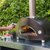 Checking the temperature using an infrared thermometer heat gun inside an Alfa One Nano wood fired pizza oven while cooking a pizza in the backyard