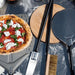Alfa Pizza Peel Set on stainless steel prep table with margherita pizza on large peel in outdoor kitchen