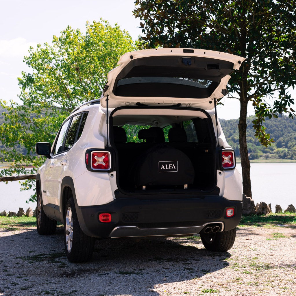 Alfa Portable Pizza Oven Cover on the oven in a white SUV with open trunk near a lake and trees