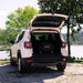 Alfa Portable Pizza Oven Cover on the oven in a white SUV with open trunk near a lake and trees