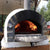 Authentic Pizza Ovens Premium Pizzaioli Stone Arch Countertop Wood Fired Pizza Oven with Door Open and Wood Burning Inside in Backyard