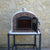 Authentic Pizza Ovens Premium Ventura Red Brick Countertop Wood Fired Pizza Oven on Back Patio on Stand with Both Doors Open and View Inside Oven