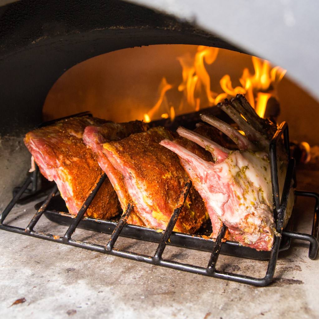 Chicago Brick Oven CBO 1000 Commercial Wood Fired Pizza Oven Kit Cooking Ribs with Wood Burning in the Background