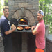 Chicago Brick Oven CBO 1000 Commercial Wood Fired Pizza Oven Kit Cooking Bratwursts and Vegetables with Father and Son