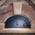 Chicago Brick Oven CBO 1000 Commercial Wood Fired Pizza Oven Kit with Door Closed in Custom Red Stone Installation