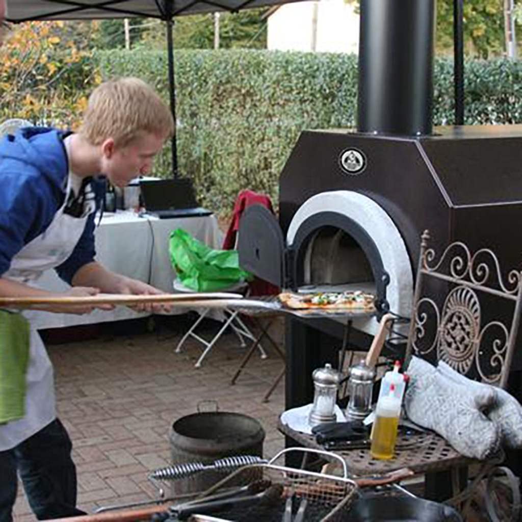 Chicago Brick Oven CBO 500 Countertop Wood Fired Pizza Oven Copper Vein with Man Cooing Pizza on the Back Porch of a Business