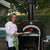 Chicago Brick Oven CBO 750 Countertop Wood Fired Pizza Oven with Chef Cooking Pizza on Back Patio with Fire Burning Inside the Oven
