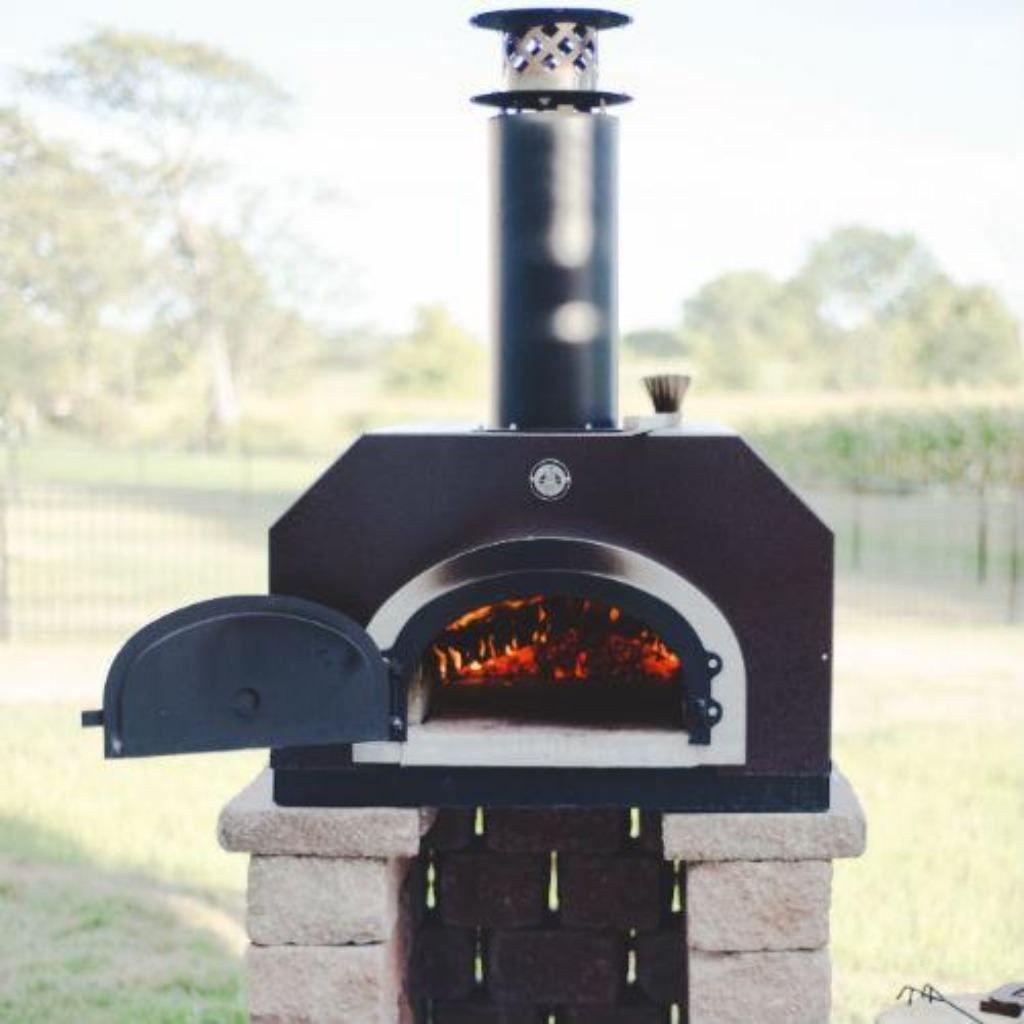 Chicago Brick Oven CBO 750 Countertop Wood Fired Pizza Oven in Copper Vein on Custom Stone Base with Door Open and Fire Burning Inside Oven