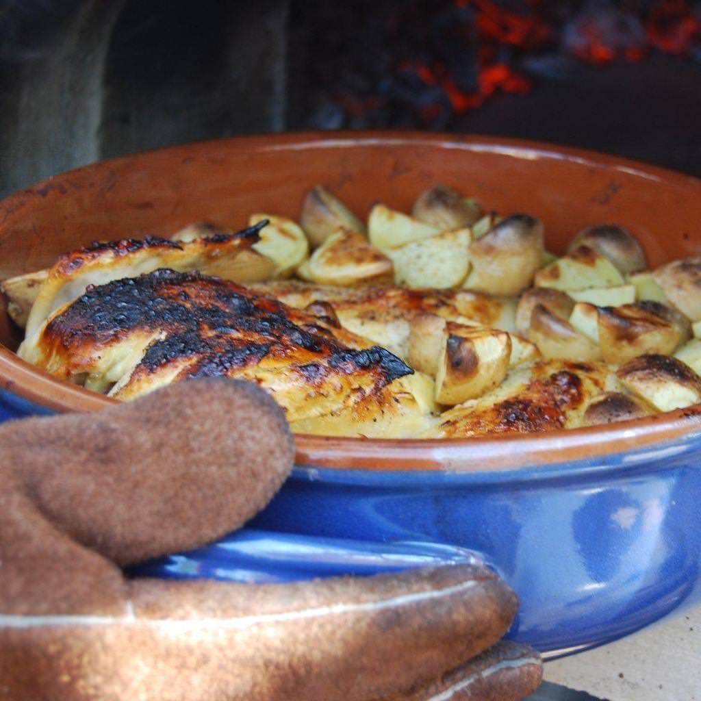 Chicago Brick Oven Mobile CBO 750 Freestanding Wood Fired Pizza Oven Cooking Chicken and Potatoes in Ceramic Baking Dish