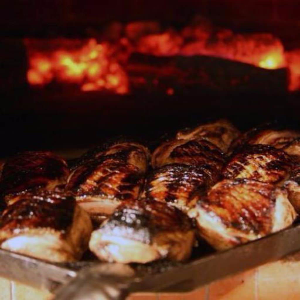 Chicago Brick Oven CBO 750 Commercial Wood Fired Pizza Oven Trailer Cooking Duck Breasts with Burning Wood in the Background
